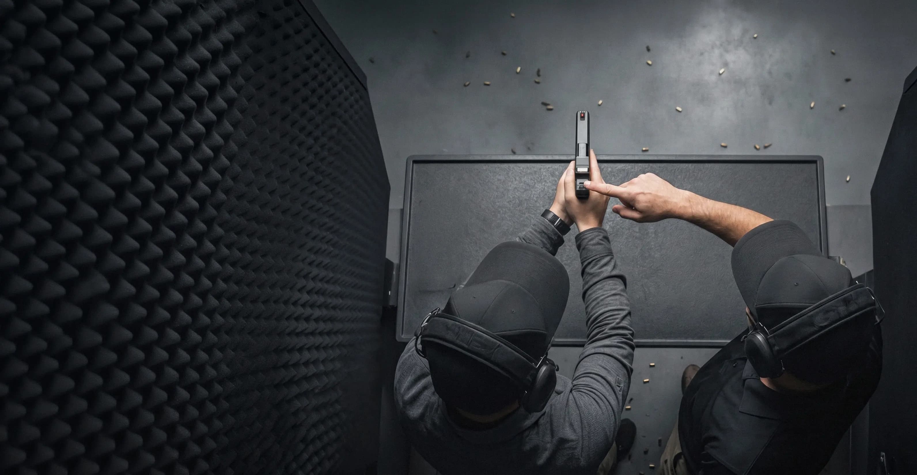 Overhead view of two licensed owners handling a pistol during Skills Builder practice
